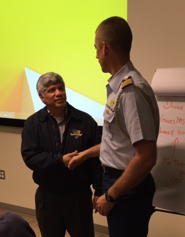AMU professor Dr. Eduardo Martinez shakes hands with USCG Captain Michael Dickey, Deputy Commander of the USCG Cyber Command after presenting student research and recommendations about how the USCG can enhance maritime cybersecurity at the USC campus. 